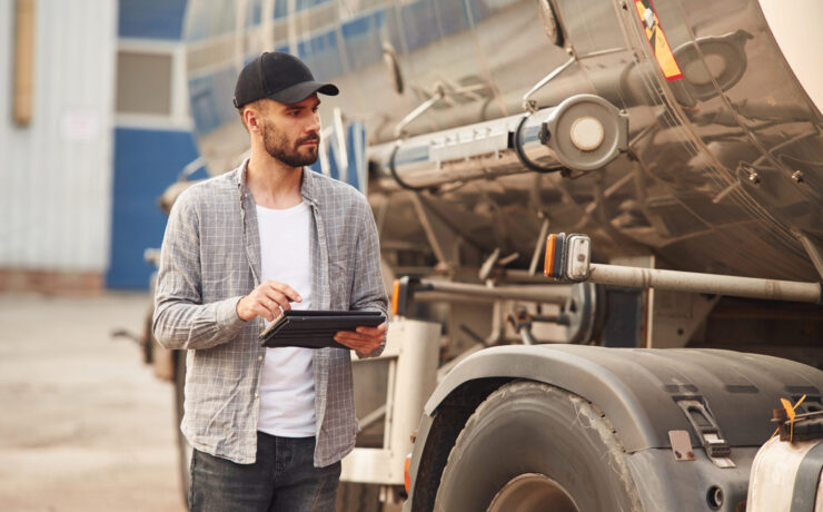 Using tablet. Young truck driver in casual clothes.
